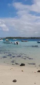 Serene beach with turquoise water and boats under a sunny sky.