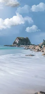 Tranquil beach with rocks under a cloudy sky at the ocean's edge.