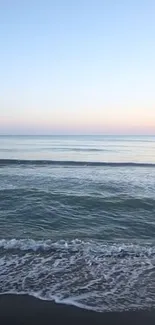 Tranquil beach scene with sunrise sky and gentle ocean waves.