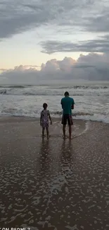 Father and daughter enjoy serene sunset on the beach.