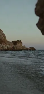 Serene beach at twilight with waves and rocky cliffs.