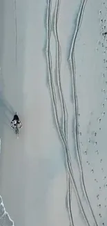 Aerial view of a bike on a sandy beach with ocean waves.