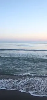 Peaceful beach with gentle ocean waves under a pastel sky.