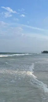 Serene beach scene with calming waves under a blue sky.