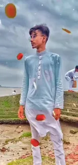 A serene beach scene with a young man in traditional attire, surrounded by falling petals.