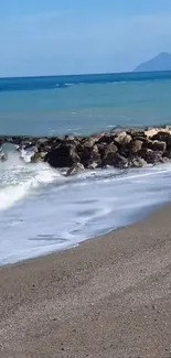 Serene beach with waves and blue sky, mobile wallpaper.