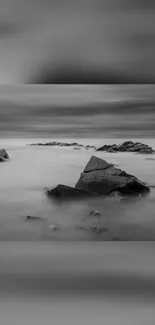 Black and white seascape with rocks and calm water on mobile wallpaper.