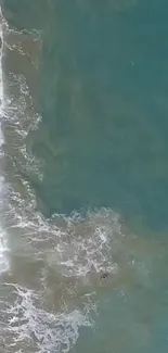 Aerial view of calm turquoise ocean waves gently meeting the shore.