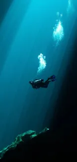 Scuba diver swimming in sunlit blue ocean depths.