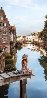 Woman sitting by a reflective canal with European buildings.