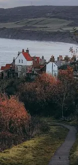 Tranquil autumn village by the sea, with rolling hills in the background.