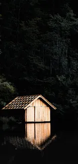 A wooden cabin reflects on a dark forest lake, creating a serene natural scene.