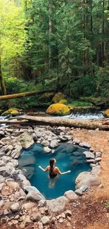 Person relaxing in a tranquil forest hot spring surrounded by lush greenery.