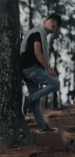 Man leans on tree in tranquil forest setting for wallpaper.