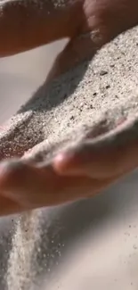 Hand holding fine sand against a calm background.