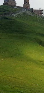 Hilltop church on lush green hill with cloudy sky.