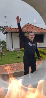 Man posing by house with visible fire effect.