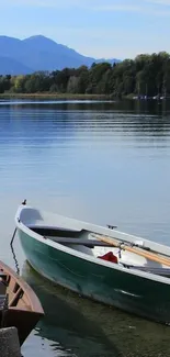 A serene lake with a wooden boat and distant mountains under a clear sky.