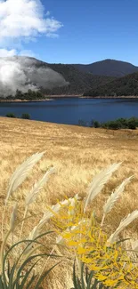 Mobile wallpaper of a serene lake, golden fields, and blue sky with clouds.