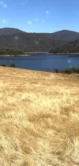 Scenic wallpaper of a lake, mountains, and golden field under a clear blue sky.