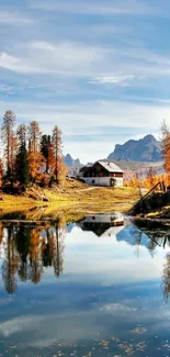 Mobile wallpaper with autumn lake and cottage reflecting in water.