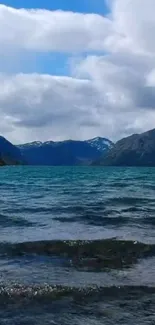 Peaceful lake with mountains under a blue sky.