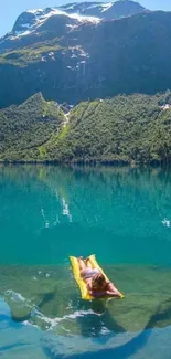 Person on yellow float in tranquil mountain lake.