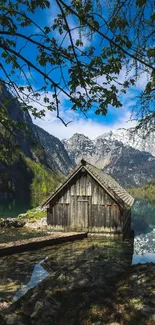 Serene lakeside cabin with mountain reflections under a vibrant blue sky.