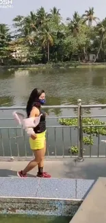 Person walks by tranquil lake surrounded by tropical greenery.