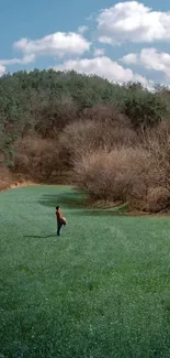 Person standing in a green meadow against a blue sky.