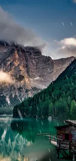 Mountain lake view with trees and cabin reflecting in water.