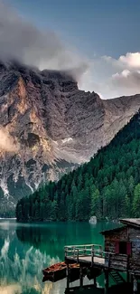 Scenic view of mountains, lake, and cabin with green forest.