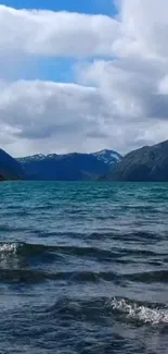 Tranquil mountain lake with blue waters under a cloudy sky.