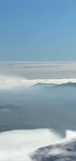 Serene mountain landscape with blue sky and misty hills.