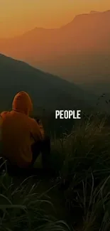 Person in a hoodie watching a mountain sunset.