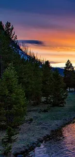 Scenic sunset over mountains and river with vivid orange and blue hues.