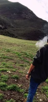 Person overlooking a tranquil green mountain landscape in mist.