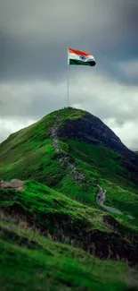 Beautiful green mountain with flag waving at the peak under cloudy skies.