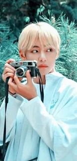 Person holding a vintage camera in nature, surrounded by greenery.