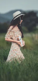 Woman in a floral dress walking through green fields with mountains in the background.