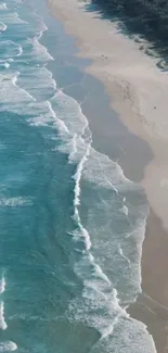 Aerial view of turquoise ocean waves hitting a sandy beach under a clear sky.