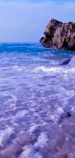 Mobile wallpaper with ocean waves and rocky cliff.