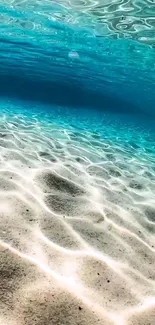 Tranquil ocean floor with sunlight on ripples and blue water hues.