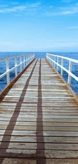 Wooden pier leading into a vast ocean under a clear blue sky.