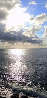 Ocean sunrise with clouds and sunlight reflecting on water.