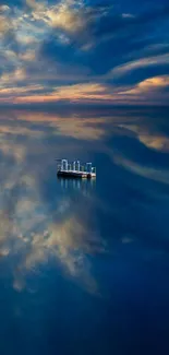 Serene ocean with a sunset sky and a lone boat reflecting on the water.