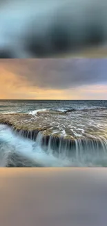 Ocean waves cascade over a rocky surface during a serene sunset.