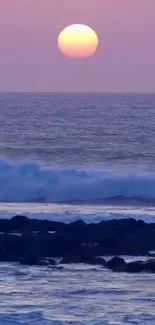 Purple ocean sunset with waves and pink sky.