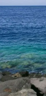 Tranquil ocean view with rocky shore and vibrant blue water.