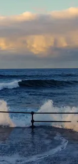 Ocean waves crash against a railing at sunset.